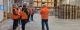 Visite d’un entrepôt logistique sous douane du Groupe Coué avec un collaborateur présentant les zones de stockage à un groupe équipé de gilets haute visibilité