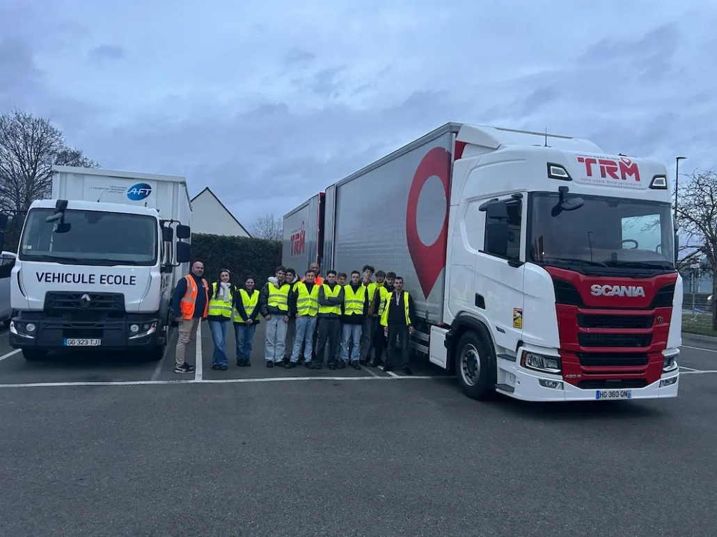 Étudiants en formation transport et logistique posant devant un camion TRM du groupe Coué lors d’une immersion terrain