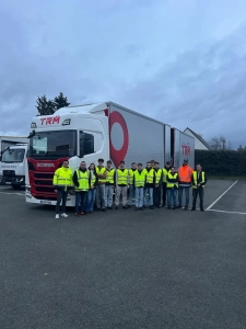Groupe d’étudiants découvrant les métiers du transport routier aux côtés d’un camion du groupe Coué TRM