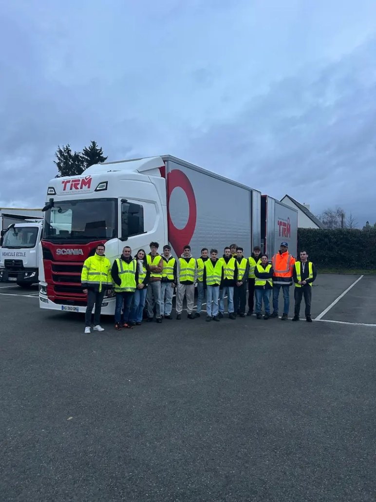 Groupe d’étudiants découvrant les métiers du transport routier aux côtés d’un camion du groupe Coué TRM