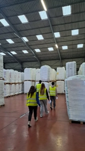 Étudiants en gilets de sécurité visitant un entrepôt logistique avec stockage palettes dans le cadre d’une formation transport